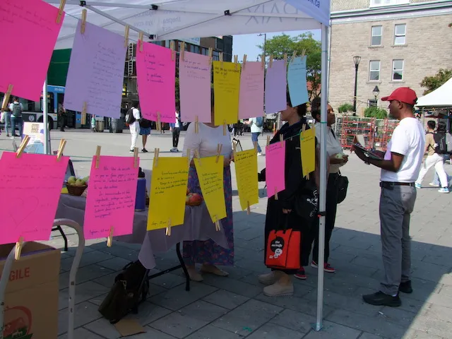 Volunteers at the IofC stand at Peace Days in Montreal, coloured notes hanging from the tent