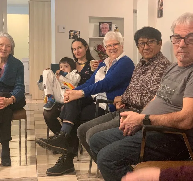 Des amis d’I&C de tous âges assis en rangée dans un salon de Montréal, souriant à la caméra