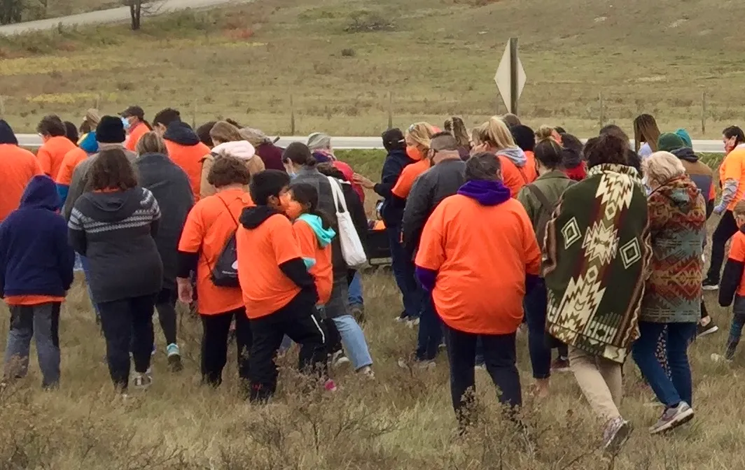 People in orange shirts walking across a field on Orange Shirt Day