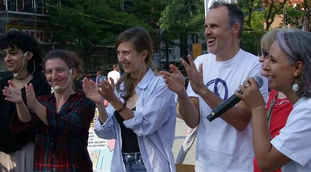 People applauding on a Montreal square at Peace Days 2023, one of them holding a microphone
