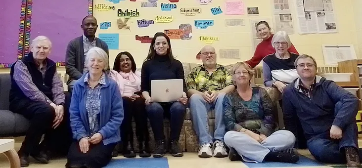 IofC friends seated together in a community room in Ottawa, one of them holding a laptop